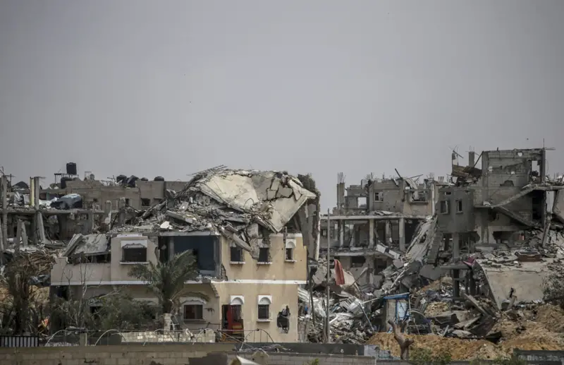 نازحون فلسطينيون يحملون عبوات قرب خزان مياه في مخيم متضرر بقطاع غزة